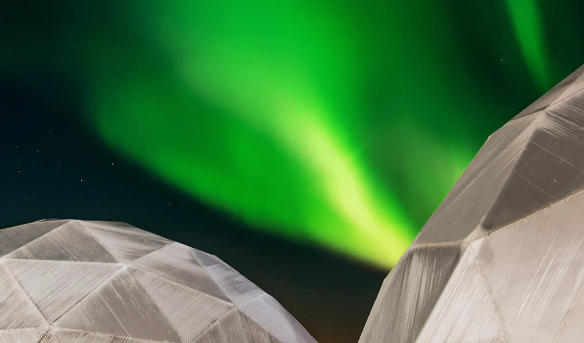 Two geodesic domes under the northern lights