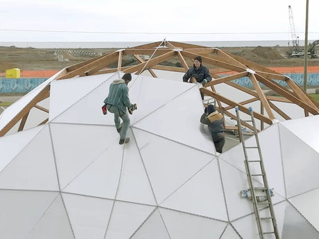 A crew on the timber frame of a large Growing Dome