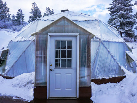The snowshed entryway and door of a Growing Dome in snow