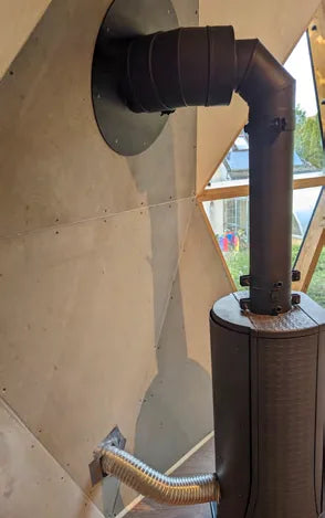 A wood stove with its flue running up through a GeoHome panel