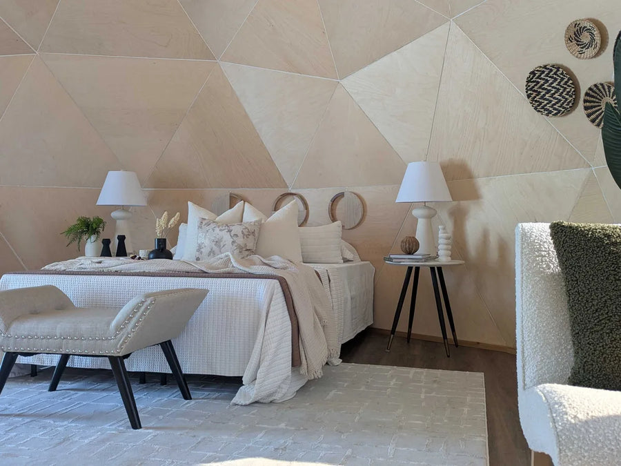 A bedroom inside a GeoHome with a bed, bench and armchair