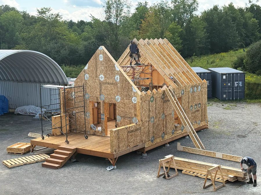 A LockFrame building going up on a gravel site with crates and a container