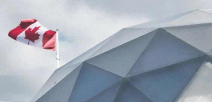A Canadian flag flying beside a dome structure